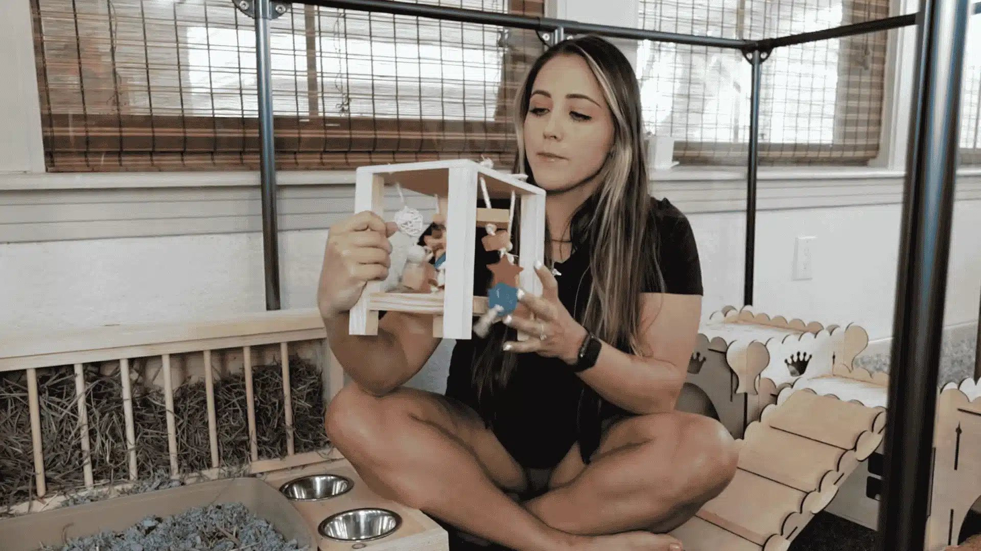 Katherine showing toys inside a bunny cage setup for rabbit enrichment and play