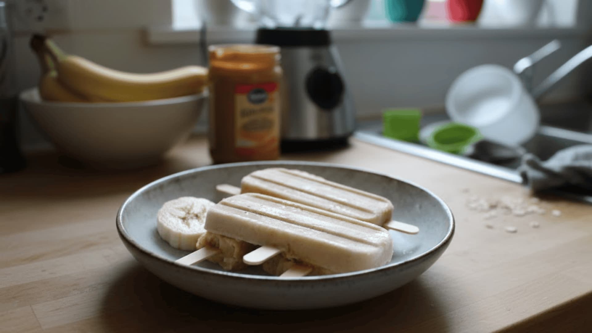 Peanut butter banana popsicles on a plate in a bright, cozy amateur kitchen setting.