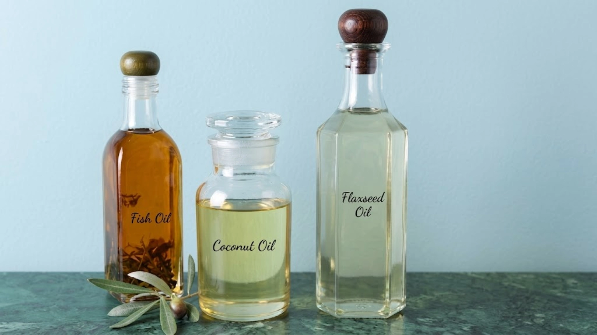 Bottles of fish oil, coconut oil, and flaxseed oil placed on a surface, showing different oil options for pet nutrition