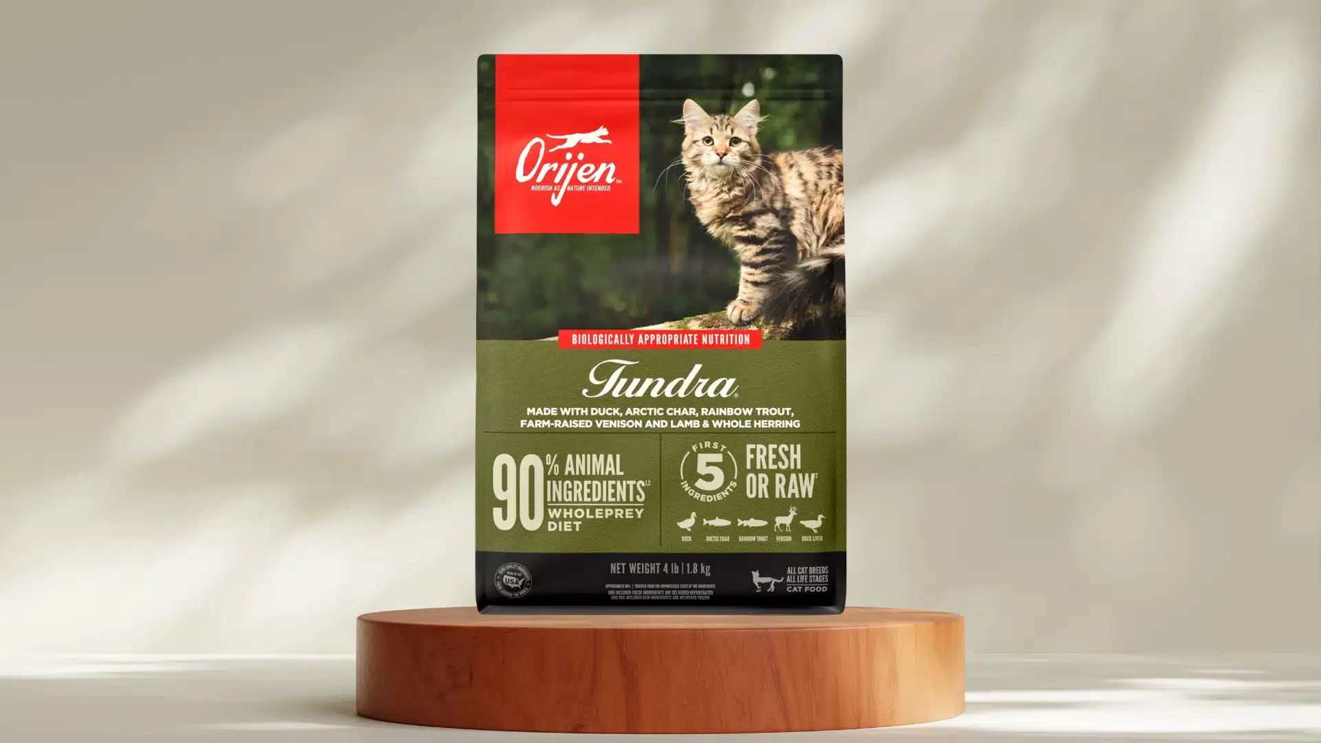 Orijen Tundra cat food bag on wooden stand with fluffy cat image and green label showing varied meat sources