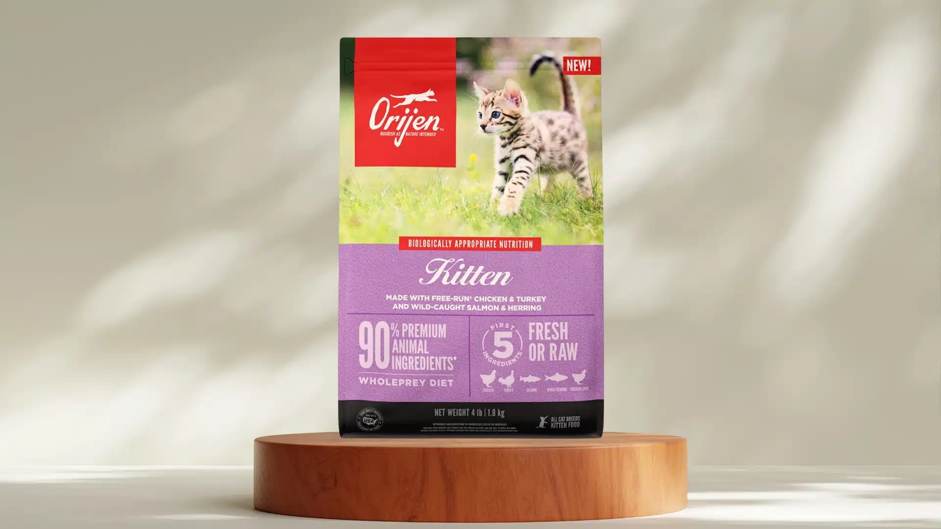 Orijen Kitten dry cat food bag on wooden stand with playful kitten image and purple label for growth nutrition