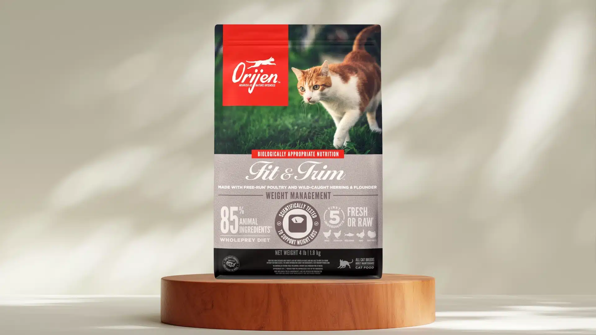 Orijen Fit and Trim dry cat food bag on wooden stand with active cat image and weight management formula