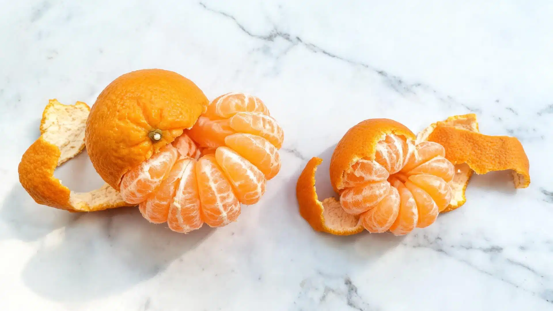 Peeled clementines and orange peels on a marble surface